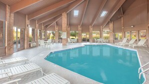 Una piscina interior con sillones de descanso y un patio cubierto.