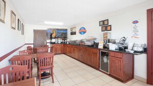 Una cocina con armarios de madera, una encimera con electrodomésticos y una zona de comedor con sillas.