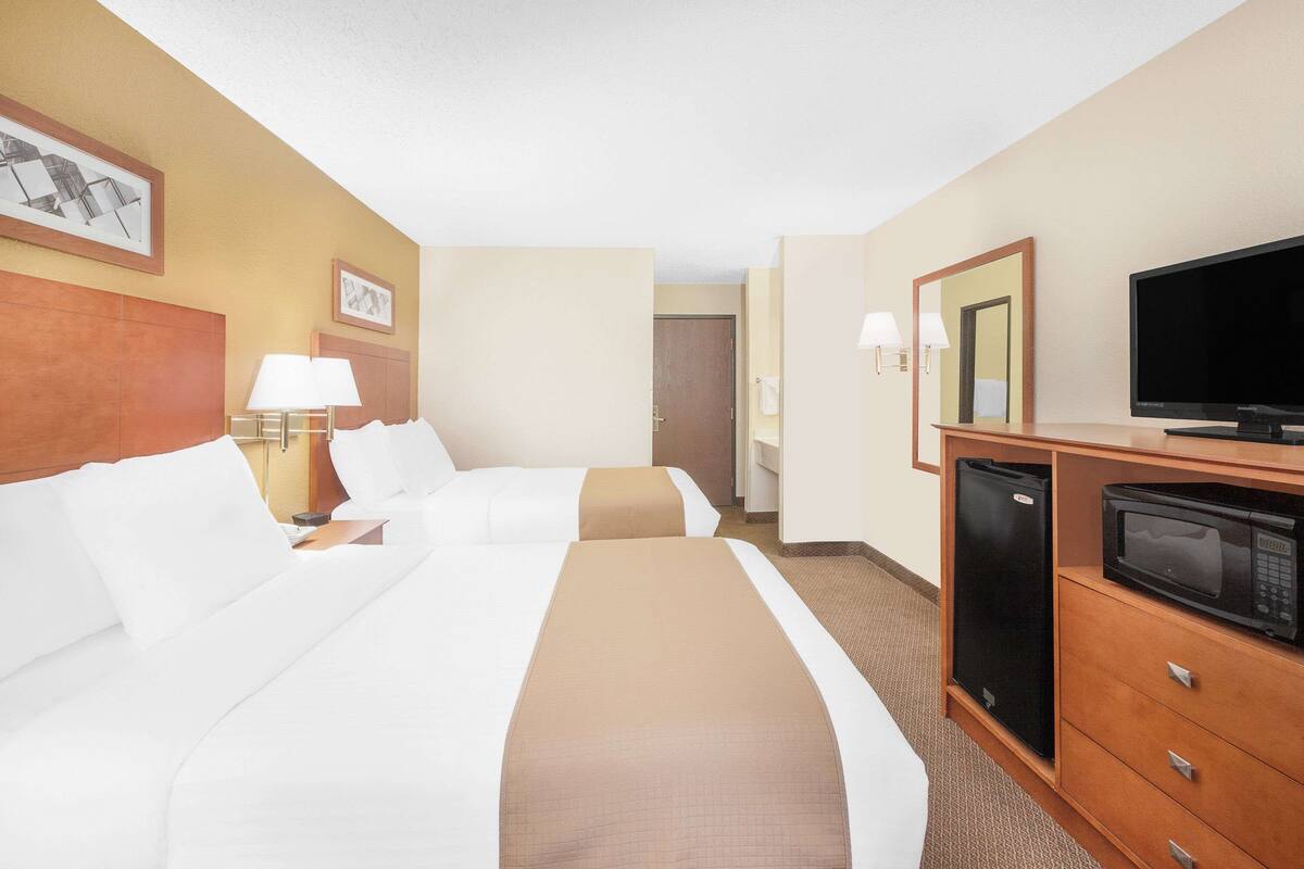 Een hotelkamer met twee bedden, een televisie, een koelkast en een magnetron.