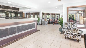 Un vestíbulo de hotel con mostrador de recepción, zona de estar y un ventilador de techo.