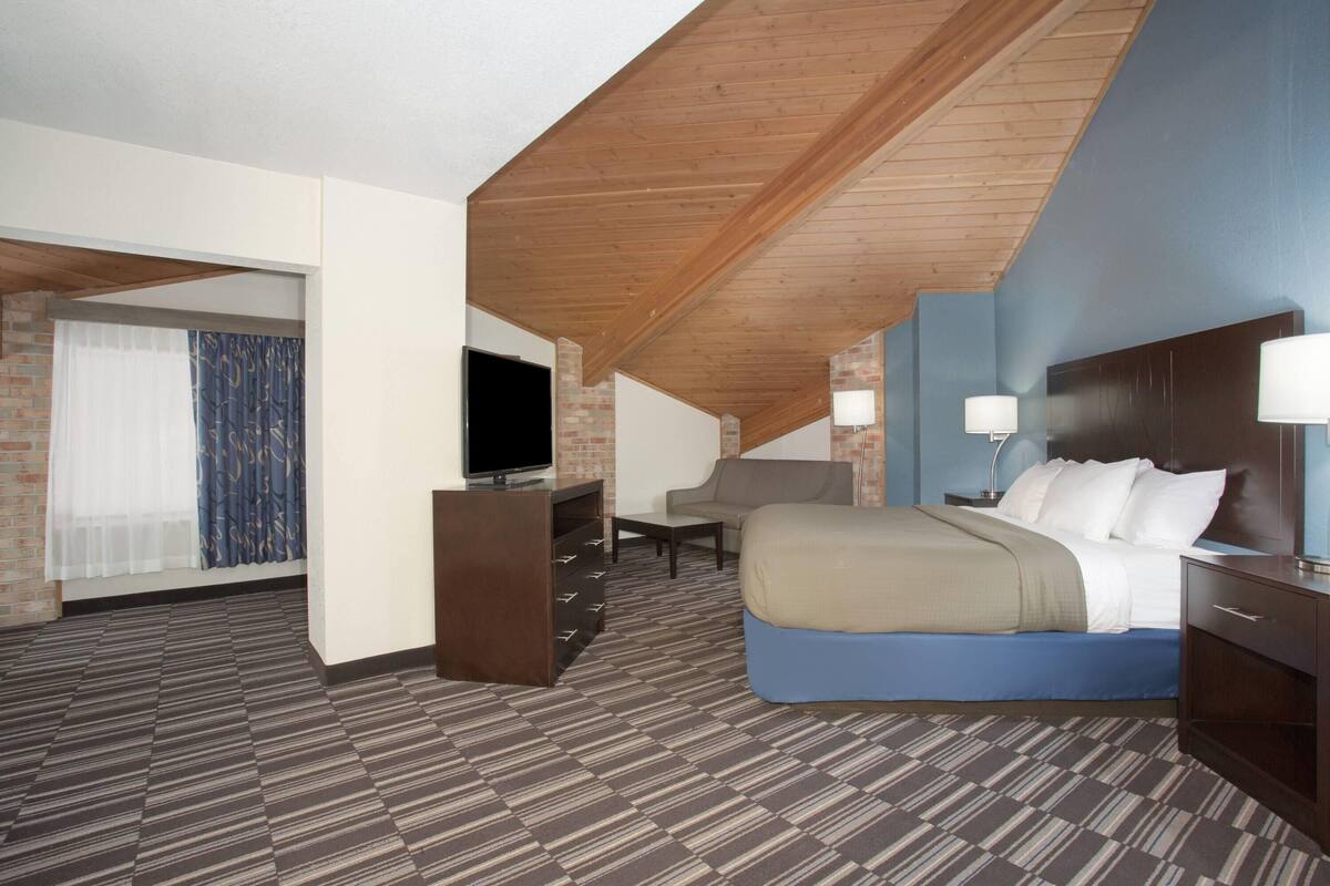 A hotel room with a bed, a TV, a desk, and a chair.