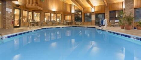 An indoor swimming pool with wooden walls and a balcony.