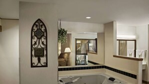 A bathroom with a large bathtub, a mirror, and a decorative wall piece. - Baymont by Wyndham Whitewater (Whitewater)