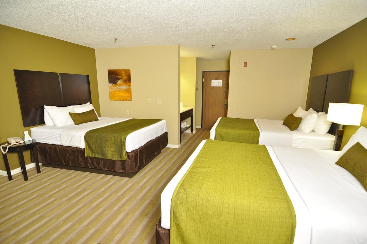 A hotel room with two beds, a desk, and a telephone.