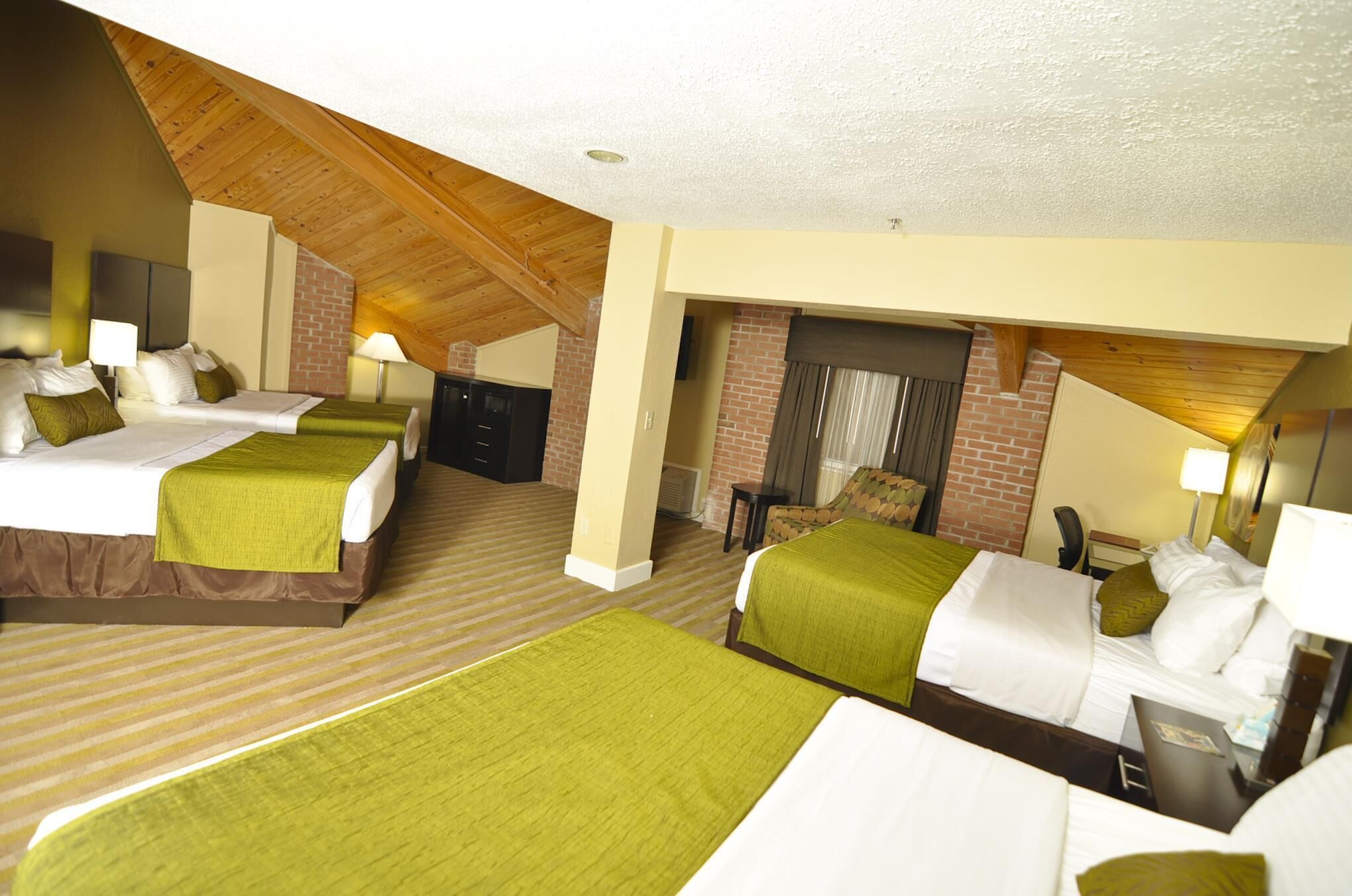 Een hotelkamer met twee bedden, een haard van baksteen en een houten plafond.