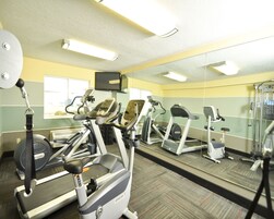 Un gimnasio con cintas de correr, elípticas y un espejo grande.