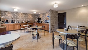 Una cocina moderna con salpicadero de piedra, armarios de madera y una zona de bar con diversos alimentos y electrodomésticos.