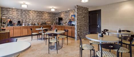 A modern kitchen with a stone backsplash, wooden cabinets, and a bar area with various food items and appliances.