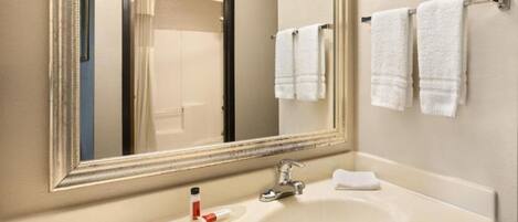 Un bagno con un grande specchio, un lavandino e due asciugamani appesi a un porta-asciugamani.