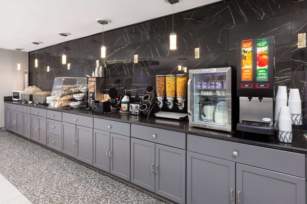A modern kitchen area with a marble backsplash, a coffee machine, a refrigerator, and a juice dispenser. - Baymont by Wyndham Warrenton (Warrenton)