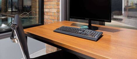 A wooden desk with a black keyboard and a Samsung monitor.