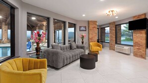 A modern living room with a gray sectional sofa, yellow armchairs, and a glass coffee table.