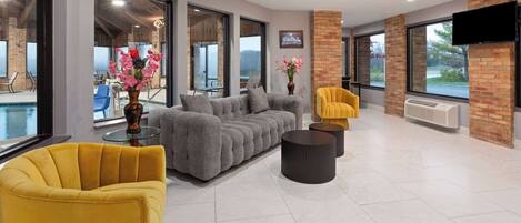 A modern living room with a gray sectional sofa, yellow armchairs, and a glass coffee table.