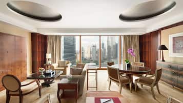 Ein geräumiges Hotelzimmer mit großem Fenster und Blick auf die Stadt, einer Essecke und einer Sitzecke mit Sofa und Sesseln.