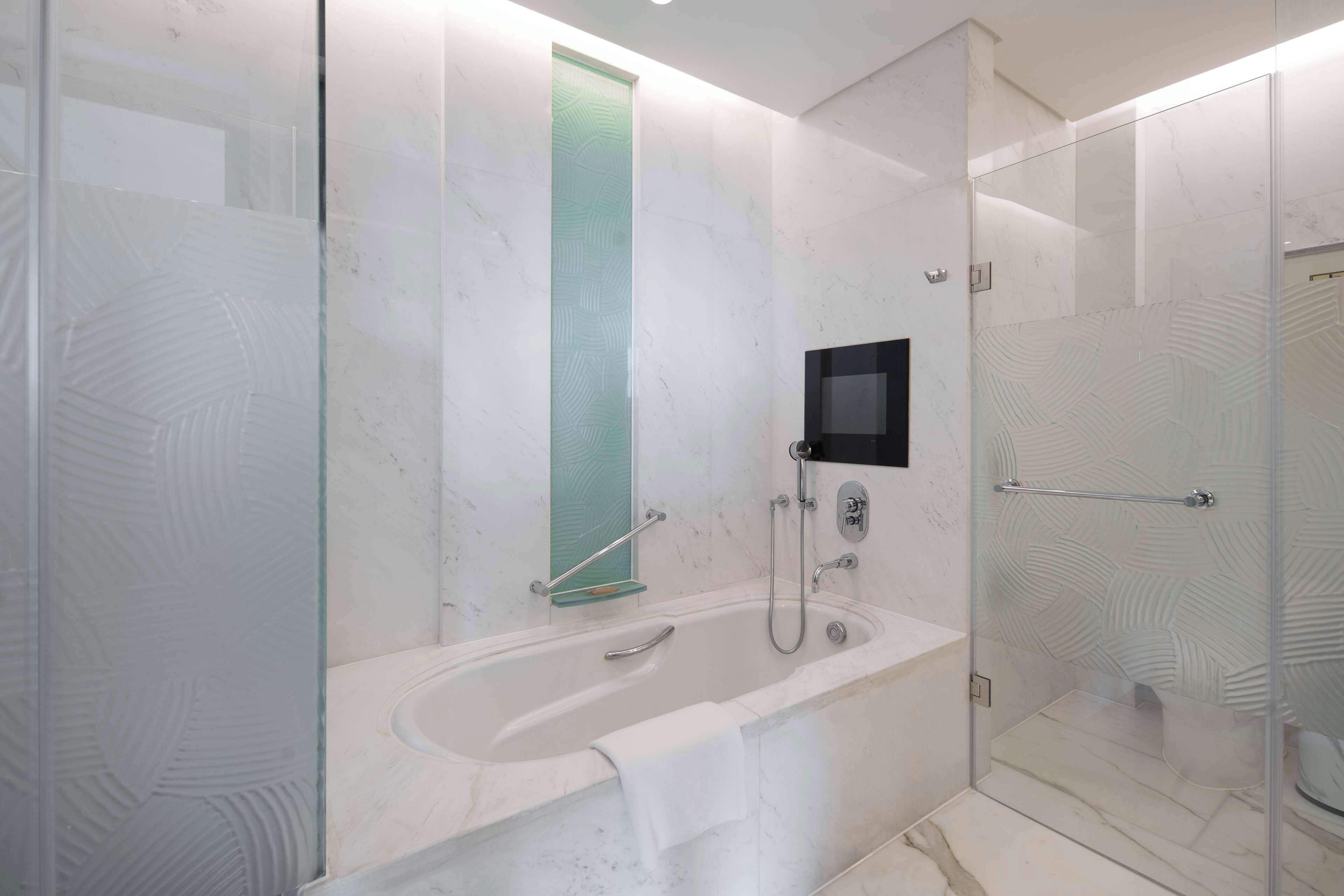 A modern bathroom with a glass-enclosed shower, a freestanding bathtub, and a glass partition.