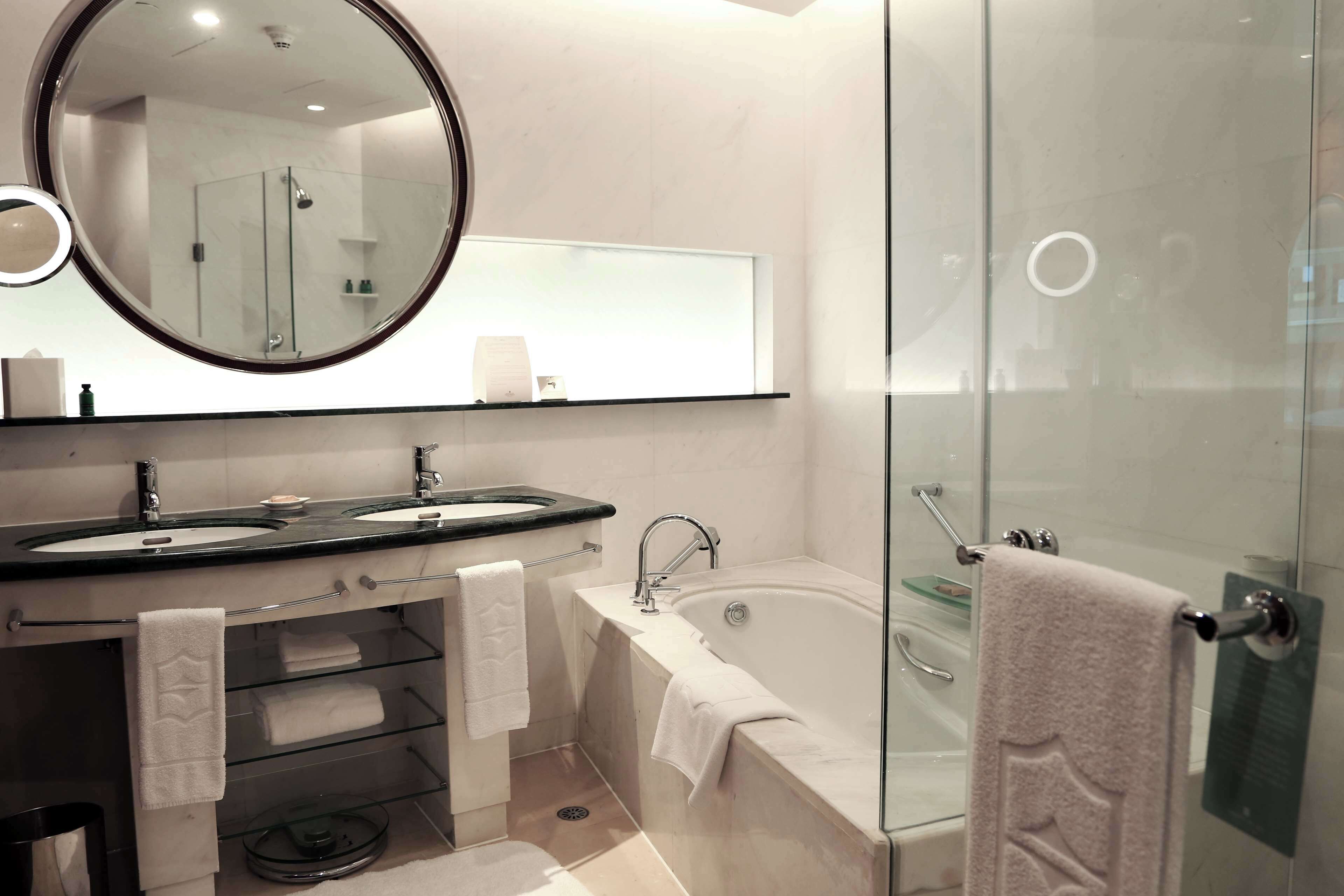 A modern bathroom with a dual sink, a large mirror, a glass-enclosed shower, and a bathtub.