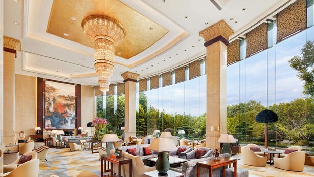 A spacious lobby with a large chandelier, comfortable seating areas, and large windows offering a view of the outdoors. - Pudong Shangri-La, Shanghai (Shanghai)