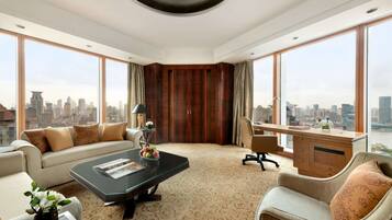 Habitación de hotel moderna con una amplia vista de la ciudad, un sofá, un escritorio y una mesa de centro.