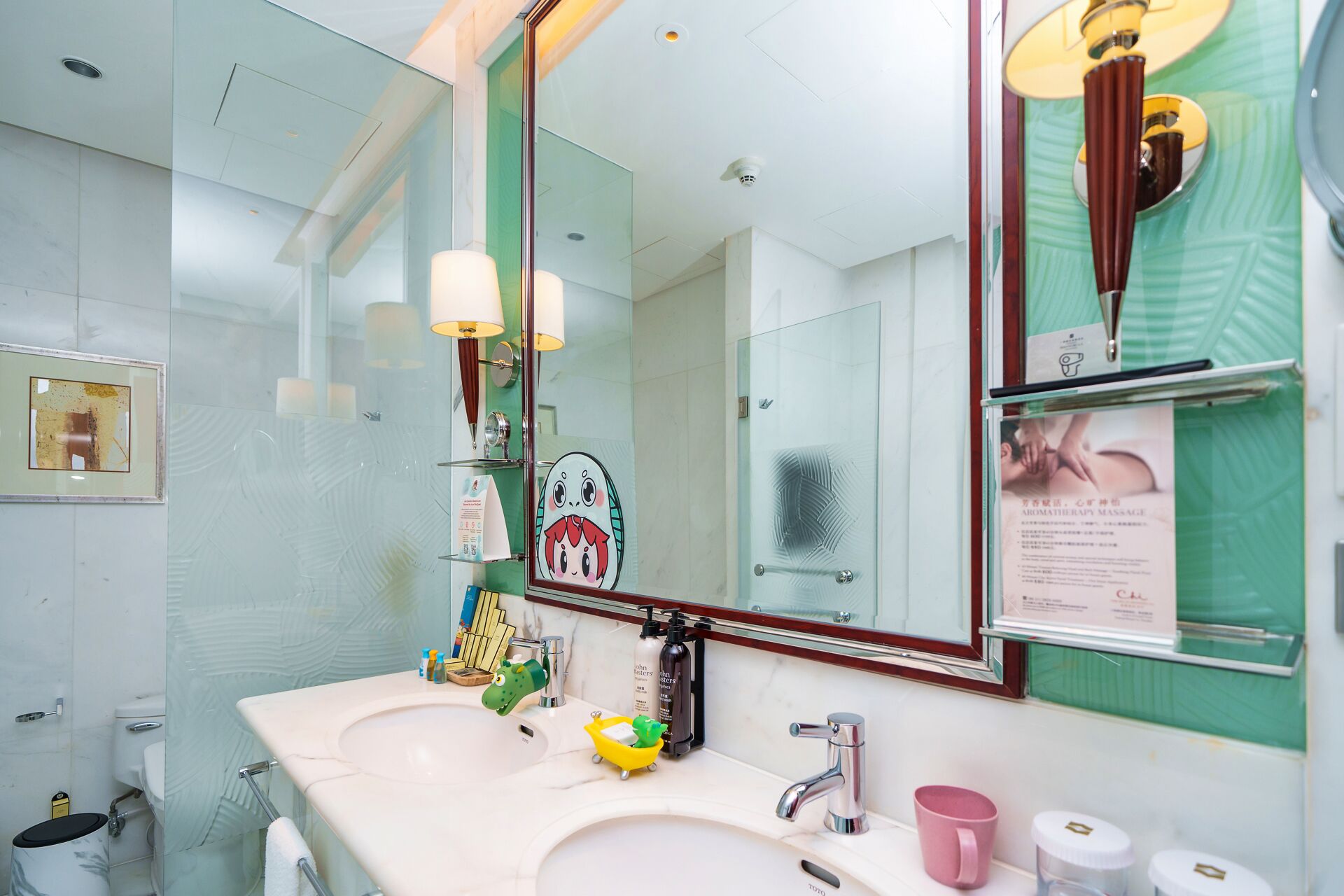 A bathroom with a white sink, a mirror, and a dinosaur-shaped soap dispenser.