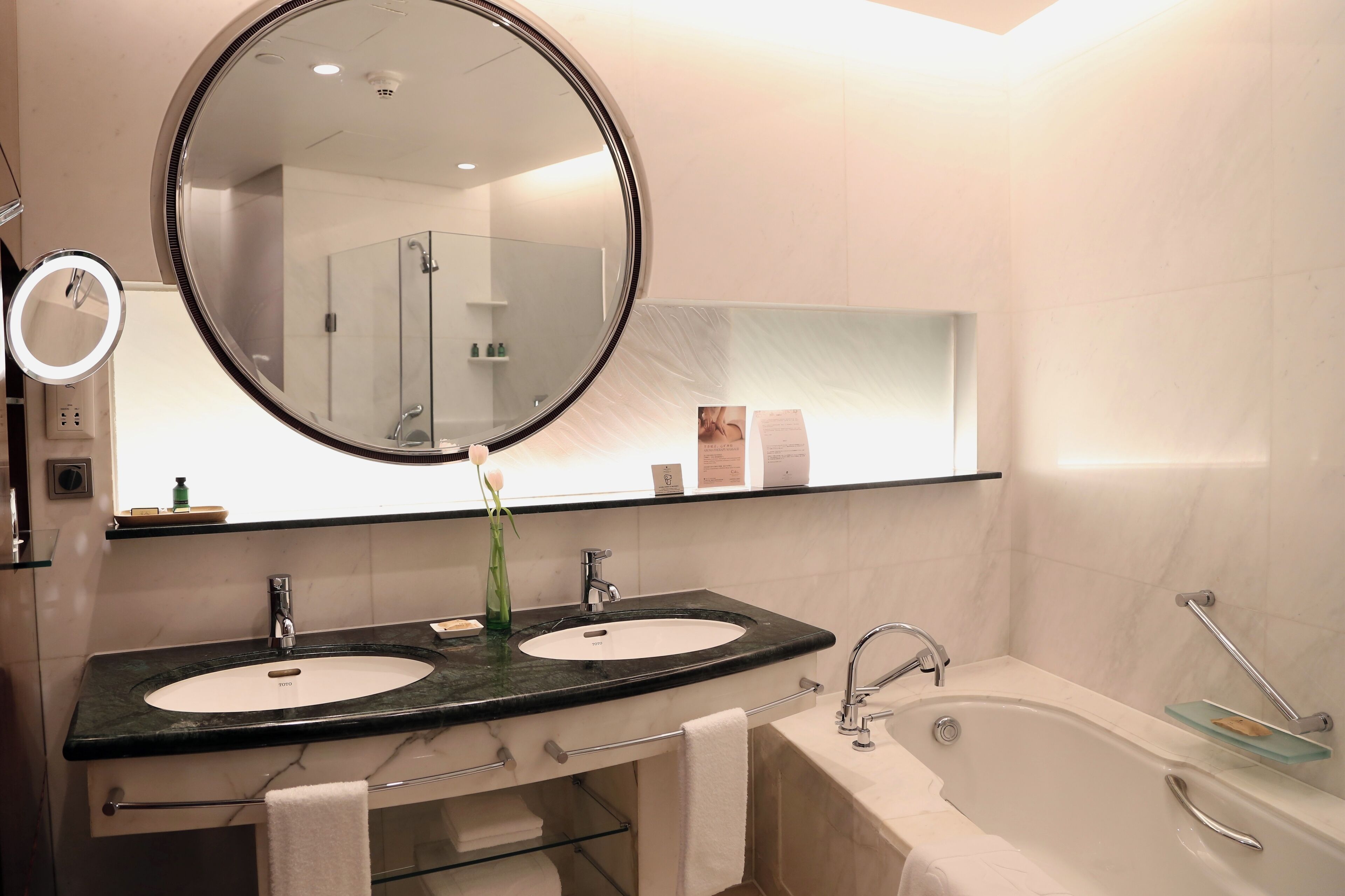 A modern bathroom with two sinks, a large mirror, and a bathtub.