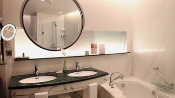 A modern bathroom with two sinks, a large mirror, and a bathtub.