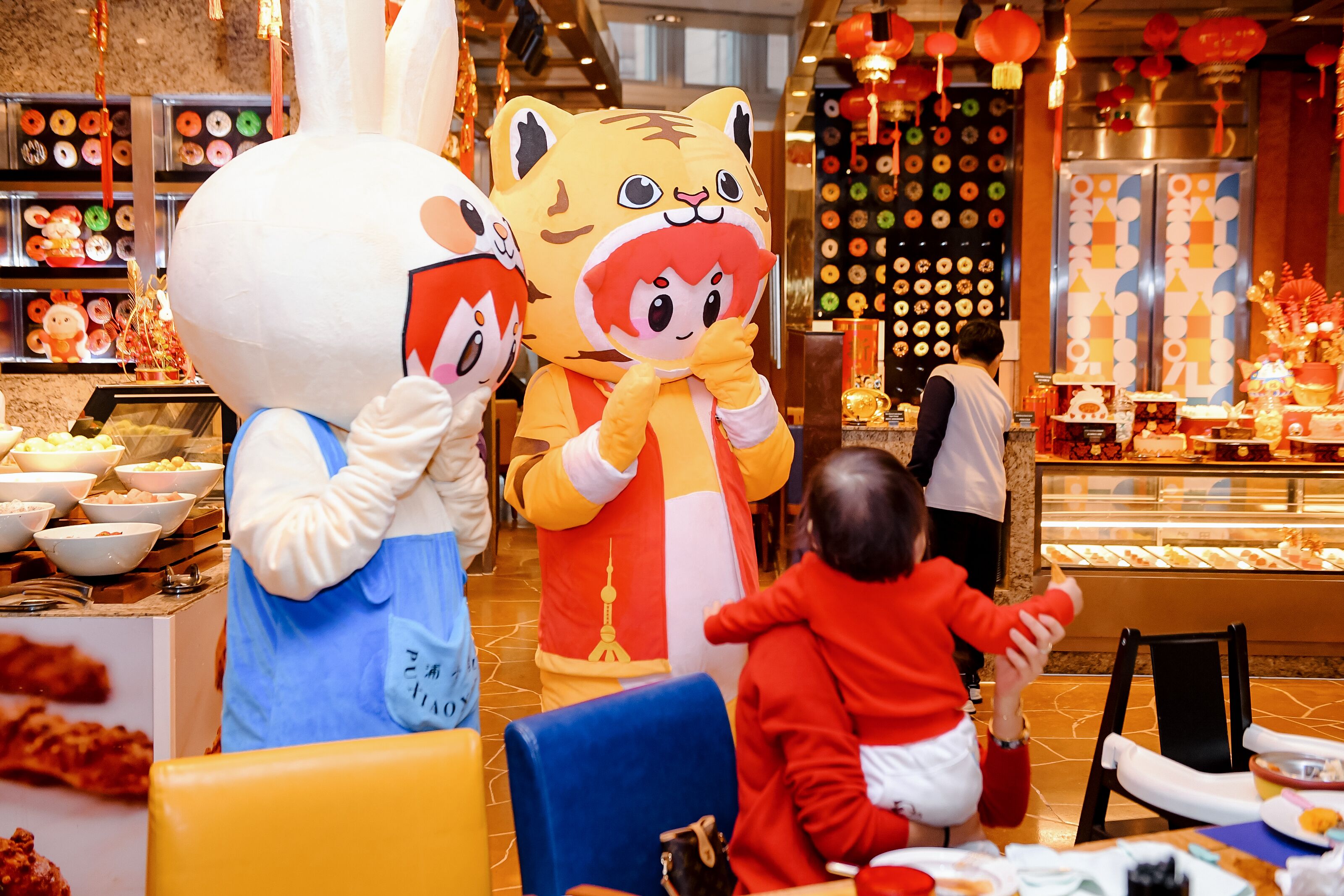 A restaurant interior with a buffet area, a display of food items, and a person in a tiger costume.