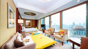 A hotel room with a bed, a desk, a chair, a TV, and a large window with a city view. - Pudong Shangri-La, Shanghai (Shanghai)