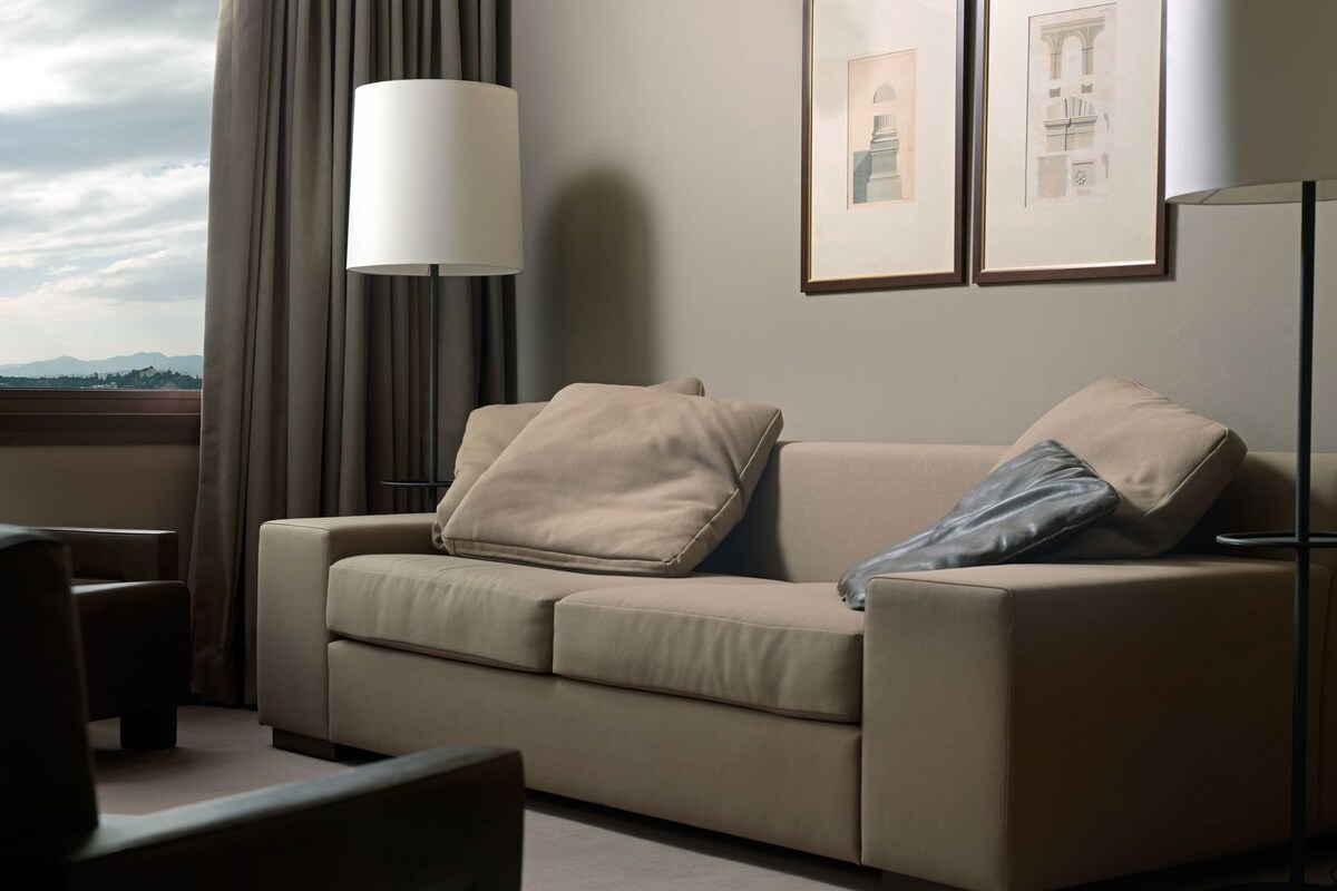 A modern living room with a sofa, a lamp, and framed artwork on the wall.