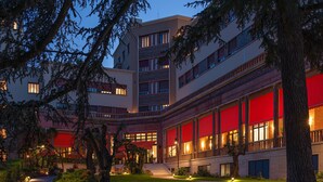 Ein mehrstöckiges Hotel mit roter Fassade, großen Fenstern und einem gepflegten Garten.