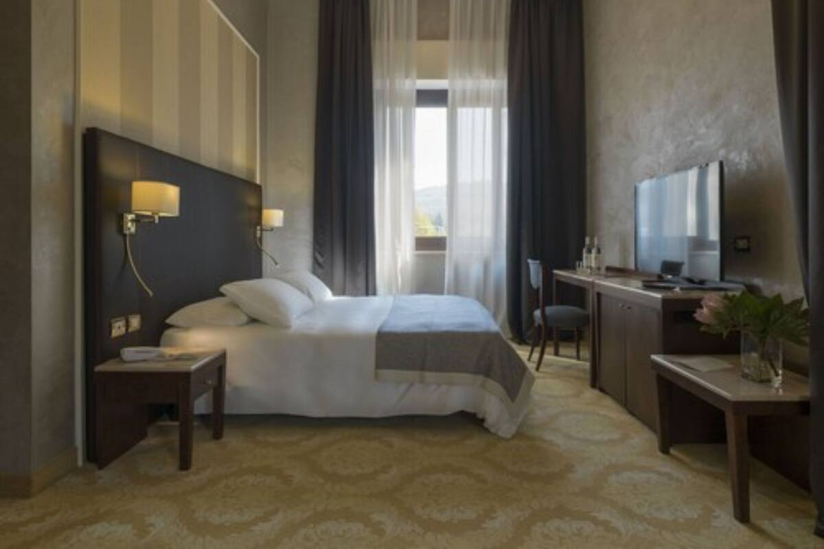 Ein Hotelzimmer mit Bett, Nachttischen, Schreibtisch, Stuhl und einem großen Spiegel.