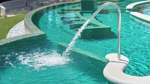 Ein Schwimmbecken mit klarem, blauem Wasser, einer Metallleiter und einem weißen Deck drumherum.