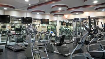 Un gimnasio con varias cintas de correr, elípticas y máquinas de pesas.