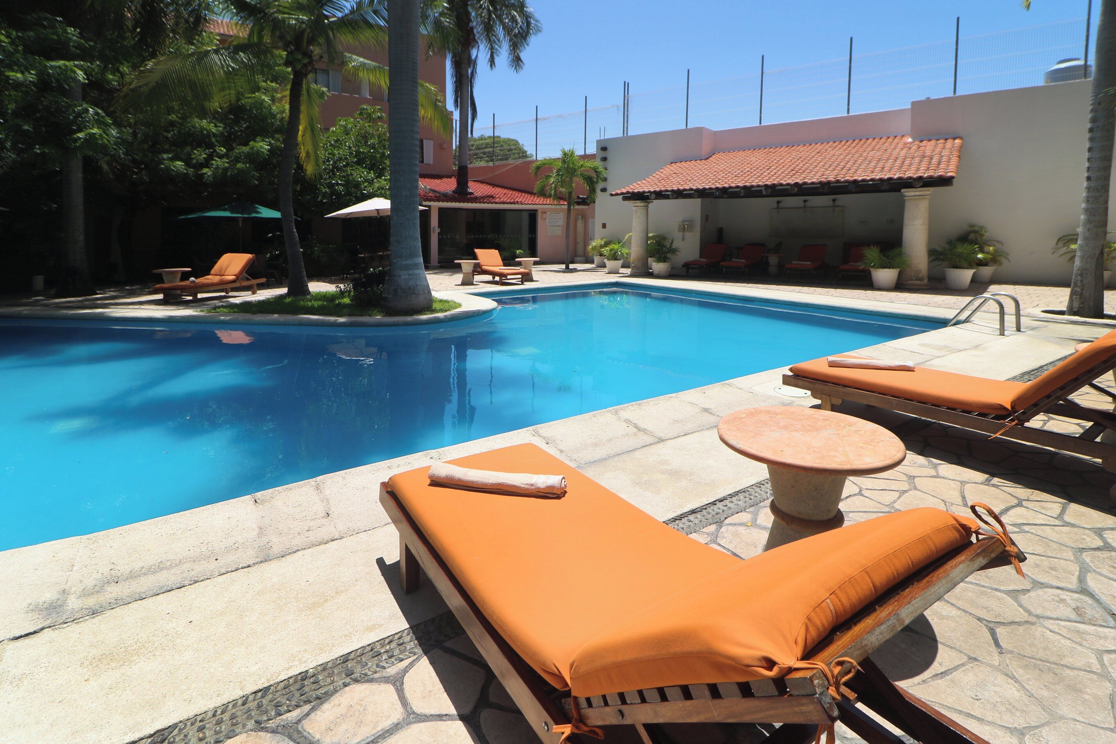 A pool area with lounge chairs and a small table.