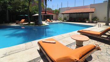 A pool area with lounge chairs and a small table.