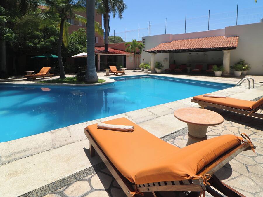 A pool area with lounge chairs and a small table.