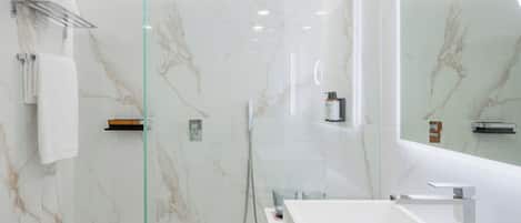 A modern bathroom with a glass-enclosed shower, a white sink, and a large mirror.