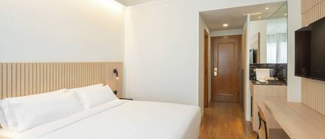 Una habitación de hotel con una cama grande, un escritorio y un espejo.