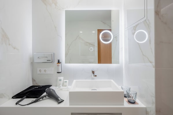 A modern bathroom with a white sink, a hairdryer, and a mirror with a circular light. - Hotel Vigo Los Galeones Affiliated by Meliá (Vigo)