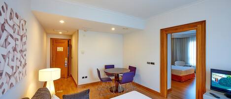 Une chambre d’hôtel comprenant un lit, un bureau avec une chaise, une télévision et une table à manger avec des chaises.