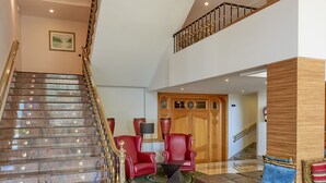 A grand staircase with a wooden finish and a glass railing, leading to a second floor. - Hotel Vigo Los Galeones Affiliated by Meliá (Vigo)