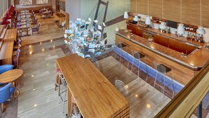 A modern hotel lobby with a bar area, seating arrangements, and a large window overlooking the interior. - Hotel Vigo Los Galeones Affiliated by Meliá (Vigo)