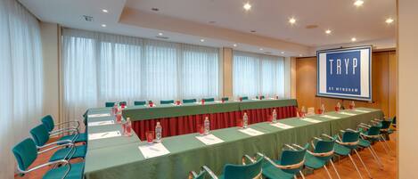 Ein Konferenzraum mit langem Tisch, Stühlen und einer Präsentationsleinwand.