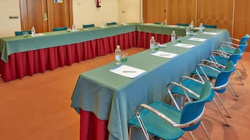 Un salón de conferencias con una larga mesa, sillas azules y botellas de agua.