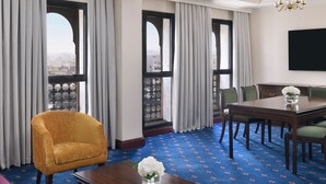 Une chambre d’hôtel avec une grande fenêtre, une table à manger, un canapé et un téléviseur.