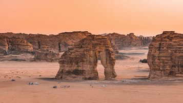 A desert landscape with rock formations and a group of people and vehicles.