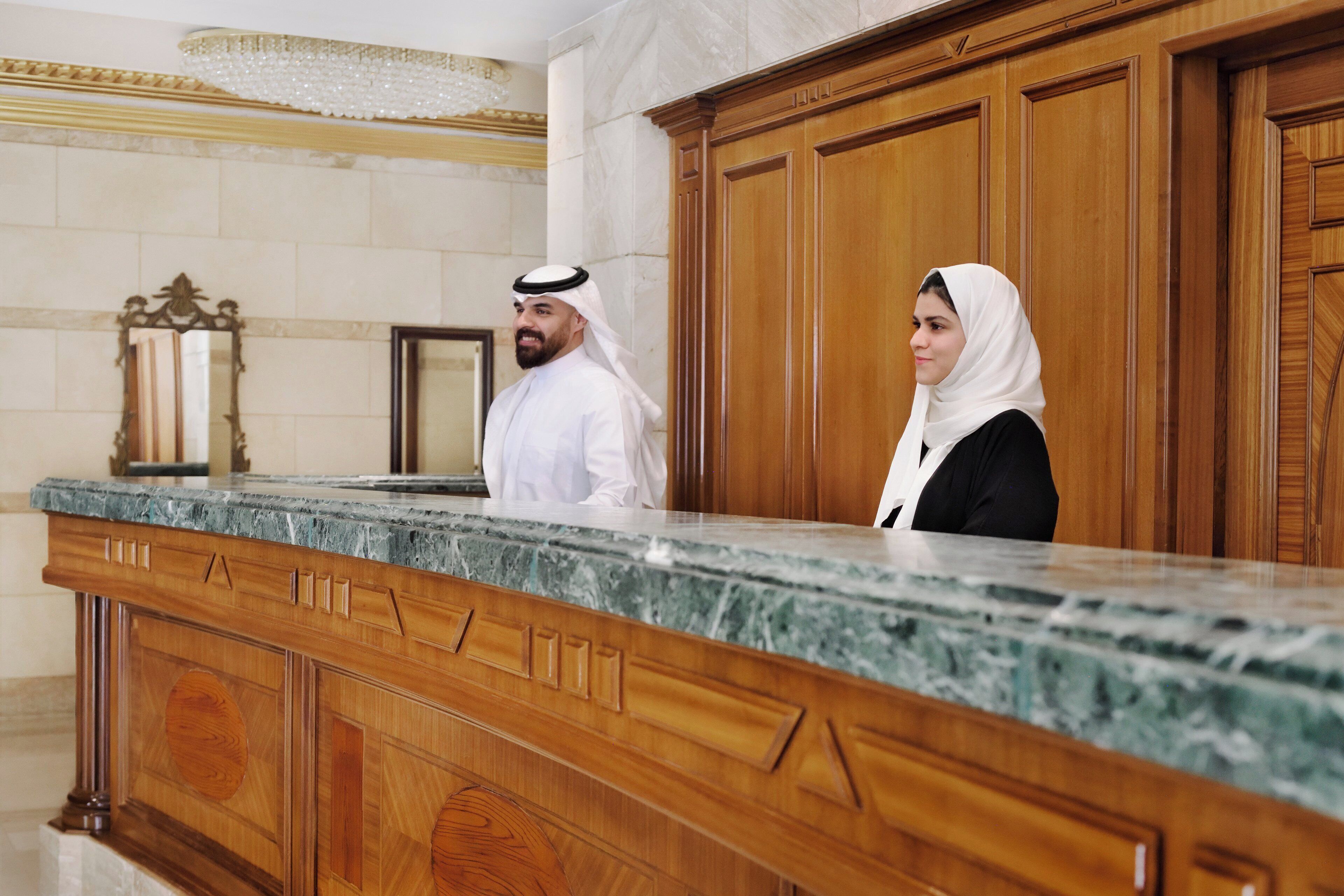 A reception desk with a marble top and wooden paneling.