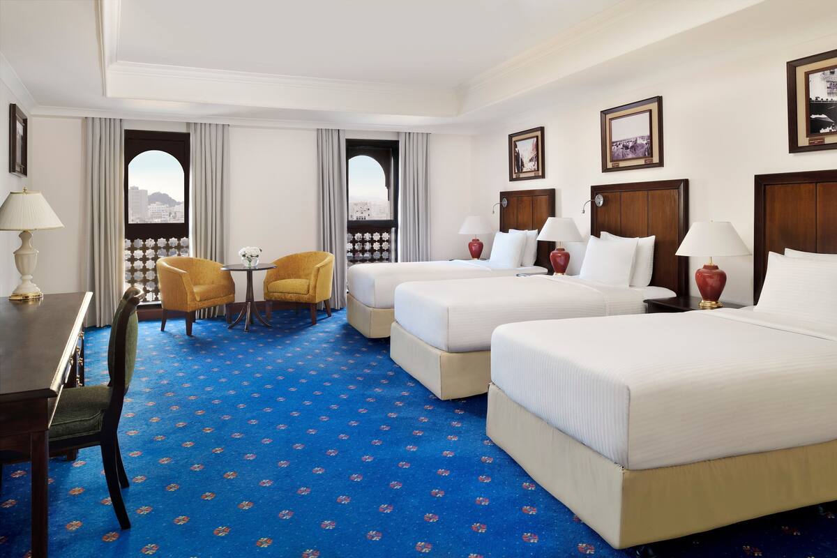 Une chambre d’hôtel avec deux lits, une table à manger, des chaises et une vue par la fenêtre.