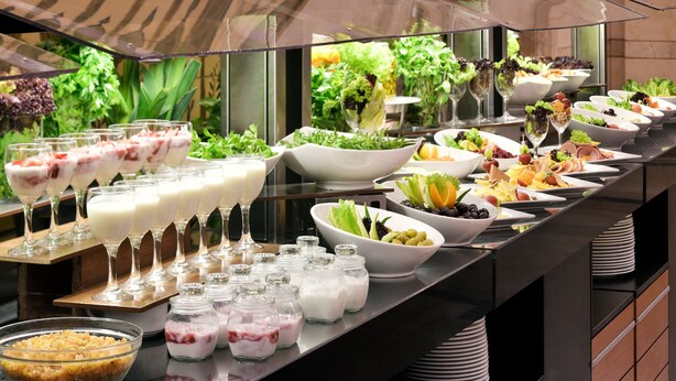 Un buffet proposant une variété de plats, notamment des salades, des fruits et des desserts.