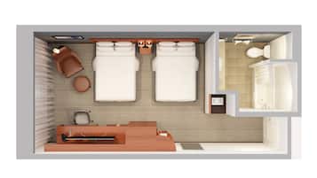 A hotel room with two beds, a desk, a chair, a small table, and a bathroom with a sink and toilet.