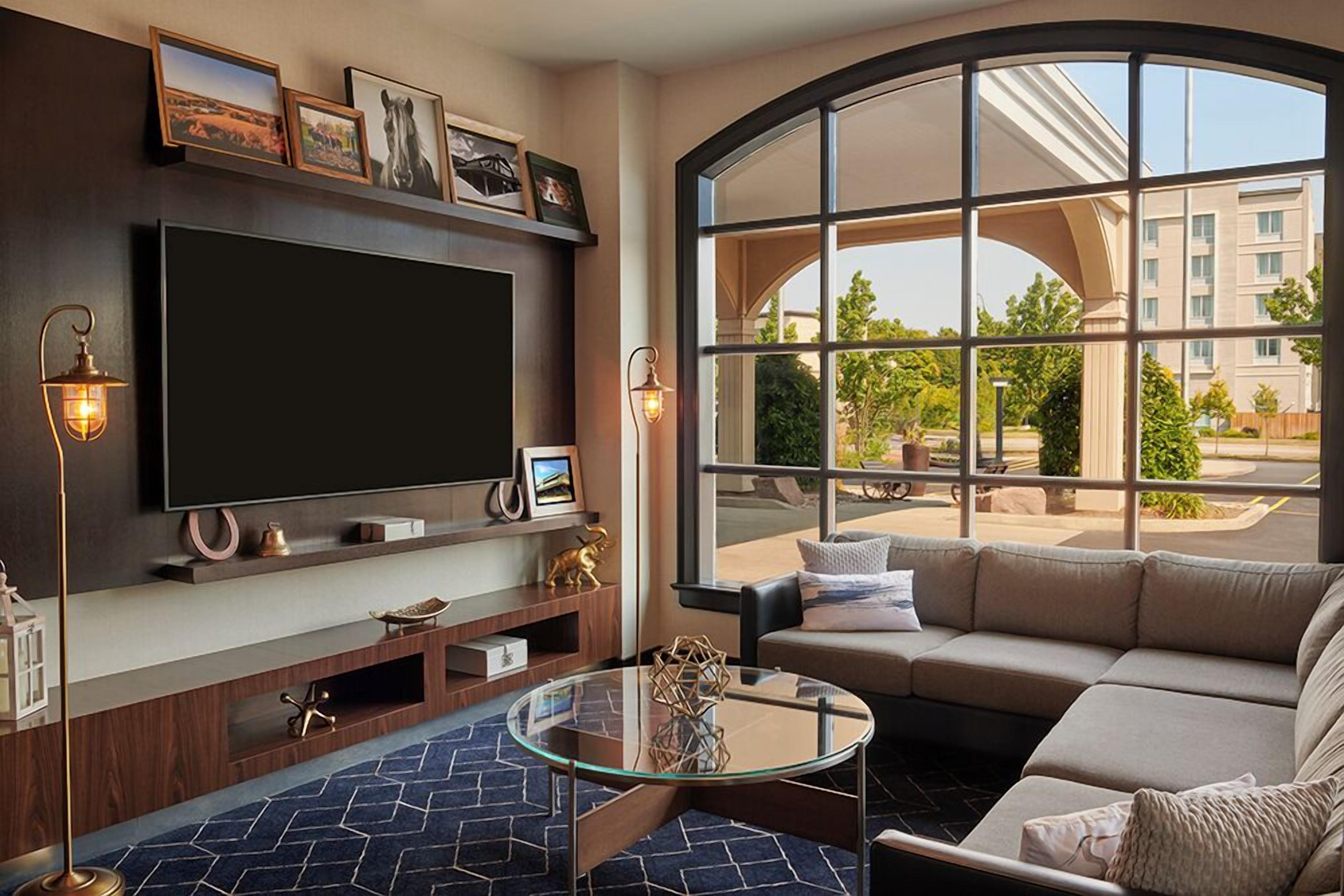 Una sala de estar moderna con televisor grande, asientos cómodos y un ventanal con vistas al exterior.